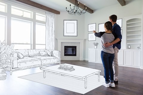 A couple is standing in a living room looking at a drawing on the wall.