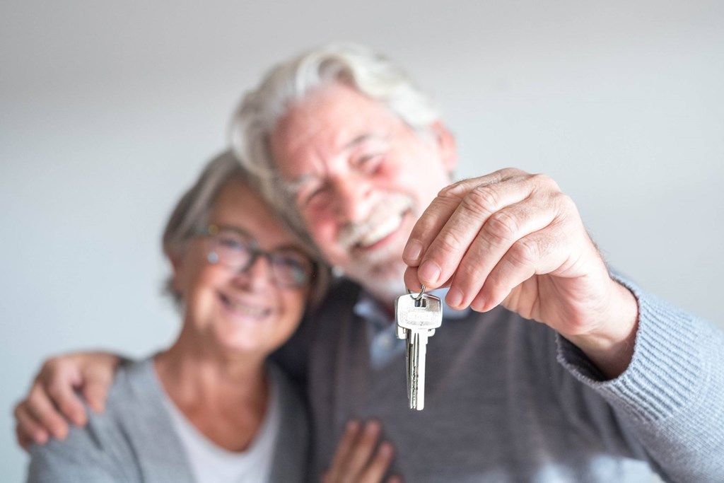 An elderly couple is holding a key together.
