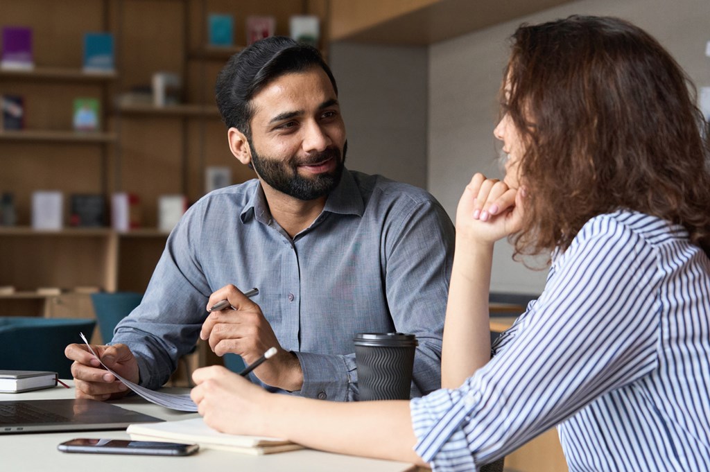 A man and a woman are having a conversation over some documents.