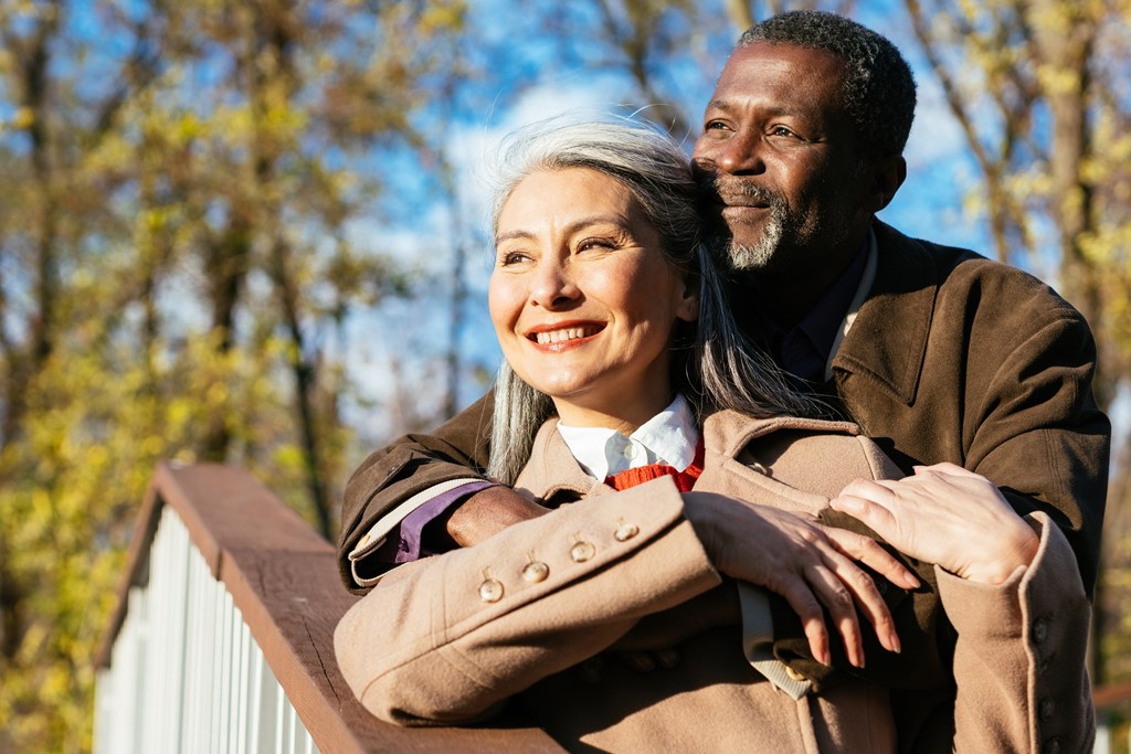 A man and a woman are standing close together on a bridge.