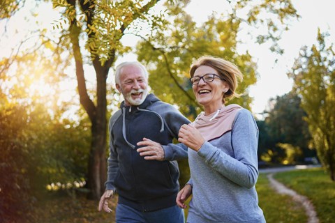 An older man and woman jogging in a park.