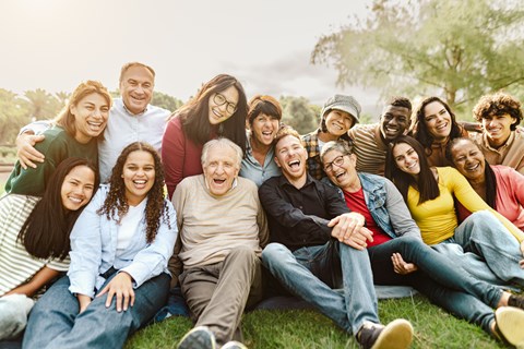 A group of people sitting on the grass in a park.
