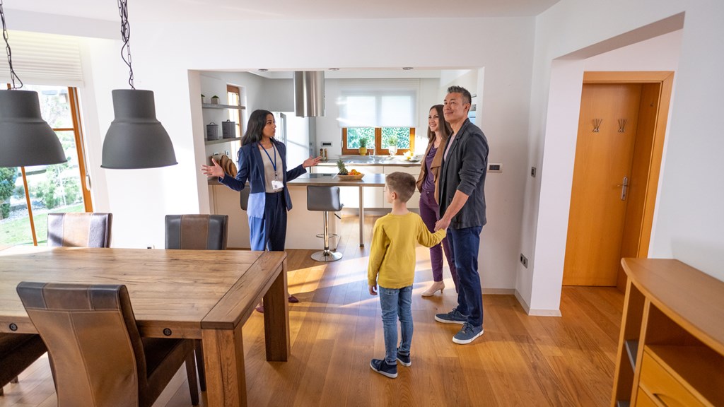 A family of three are standing in a kitchen with a child in the middle.