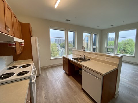 A kitchen with a white stove top oven and a white dishwasher.