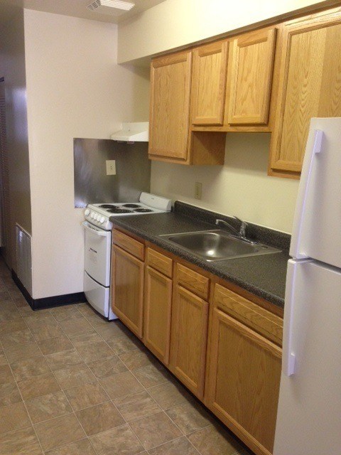 A kitchen with a white refrigerator, a black stove, and a dishwasher.
