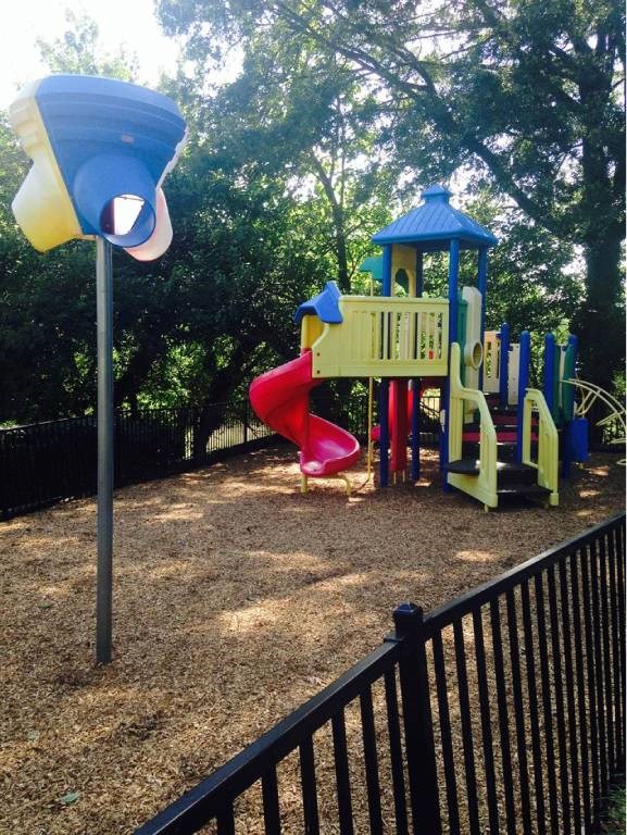 A playground with a blue and yellow tower, a red slide, and a black fence.