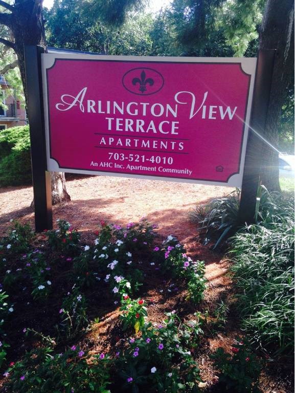 A sign for Arlington View Terrace Apartments is shown in front of some flowers.