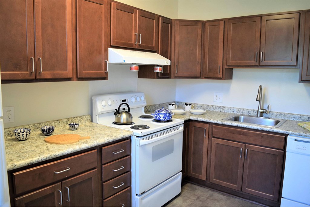 A kitchen with a white stove and brown cabinets.