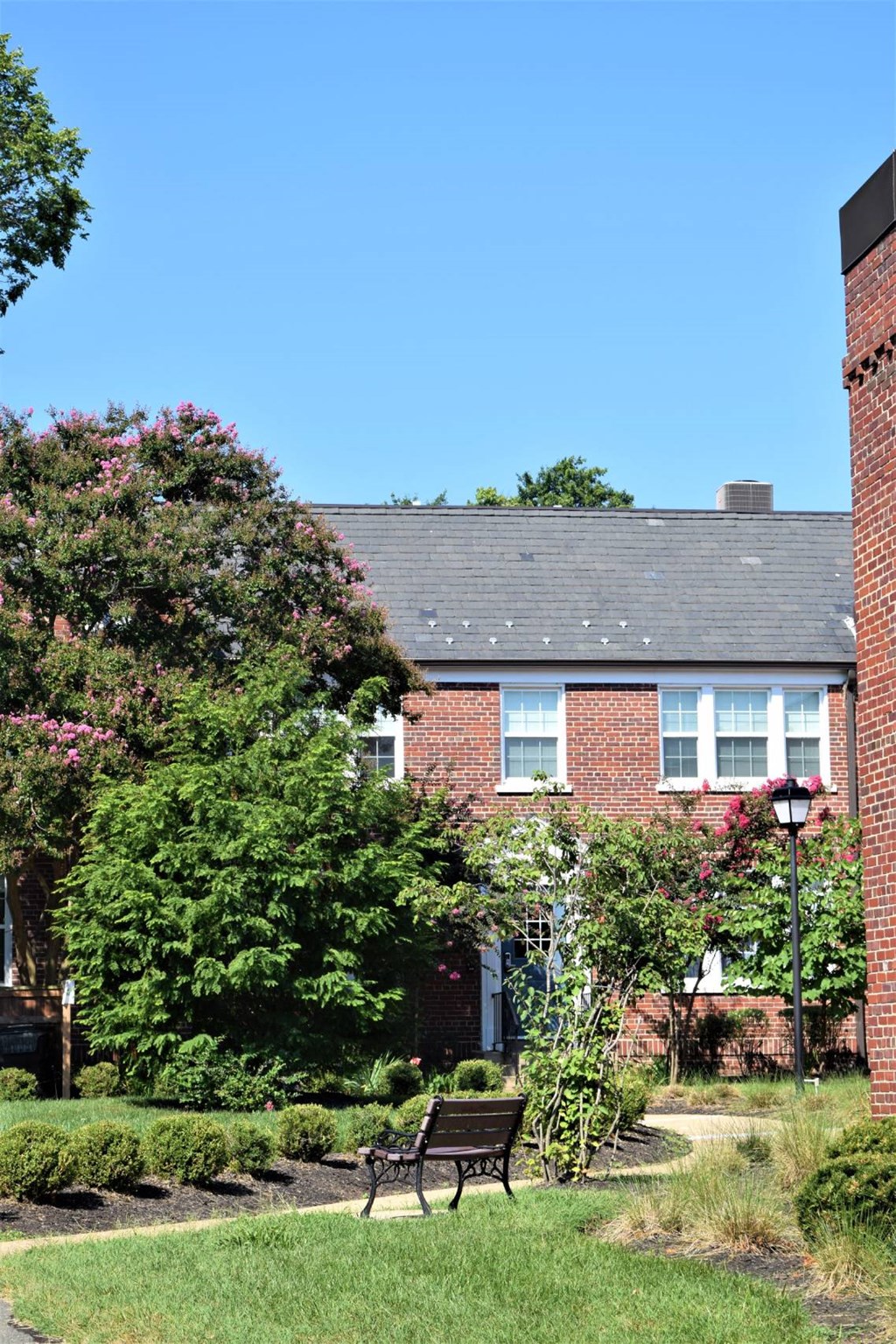 A red brick building with a black bench in front of it.