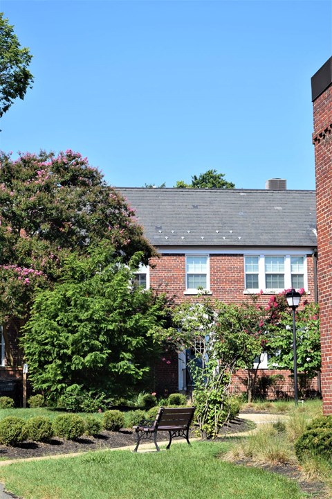 A red brick building with a black bench in front of it.