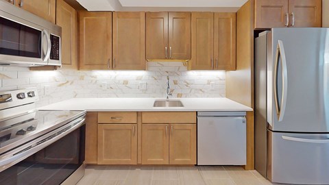 A kitchen with wooden cabinets and a marble backsplash.