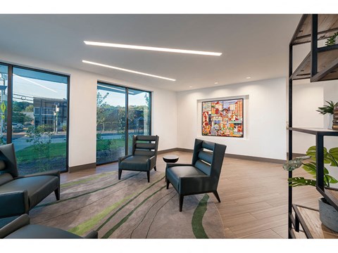 A living room with a large window and a painting on the wall.