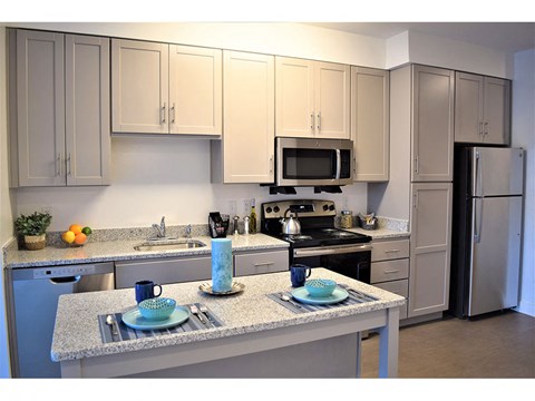 A kitchen with a granite countertop and a microwave above it.