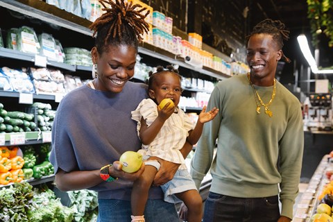 A woman and a man are shopping with a child in a grocery store.