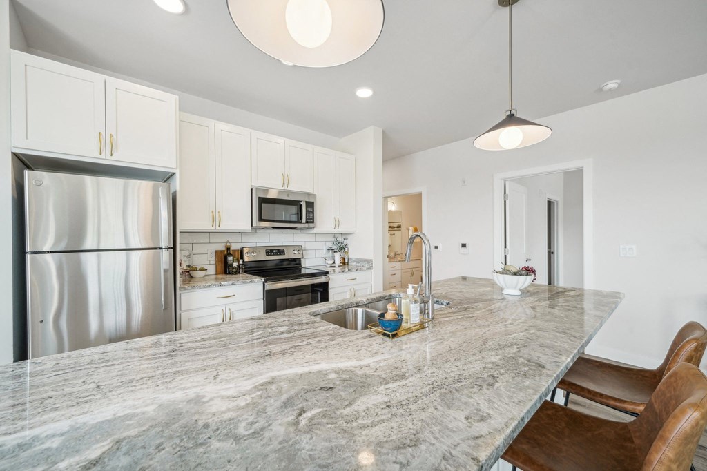 a kitchen with a marble counter top and a stainless steel refrigerator