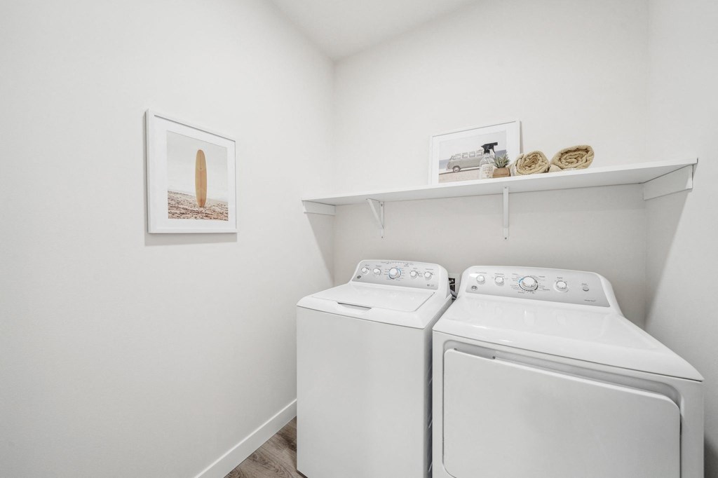 a washer and dryer in a white laundry room with white walls and shelves