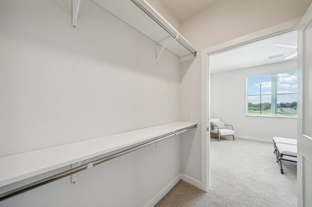 the living room of an apartment with white walls and a large window