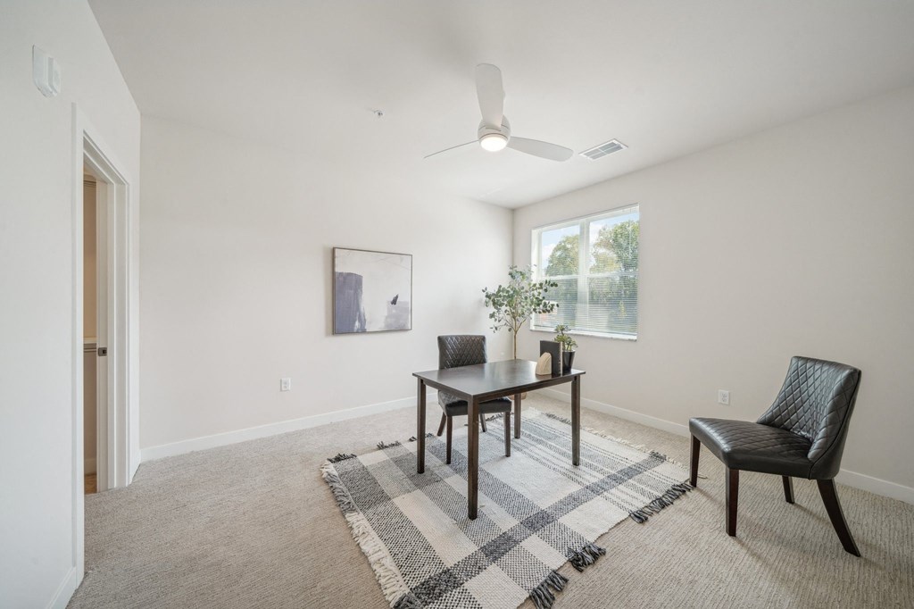 a living room with a table and chairs and a ceiling fan