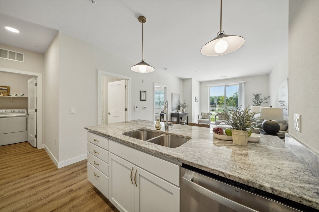 an open kitchen and living room with a counter top and a sink