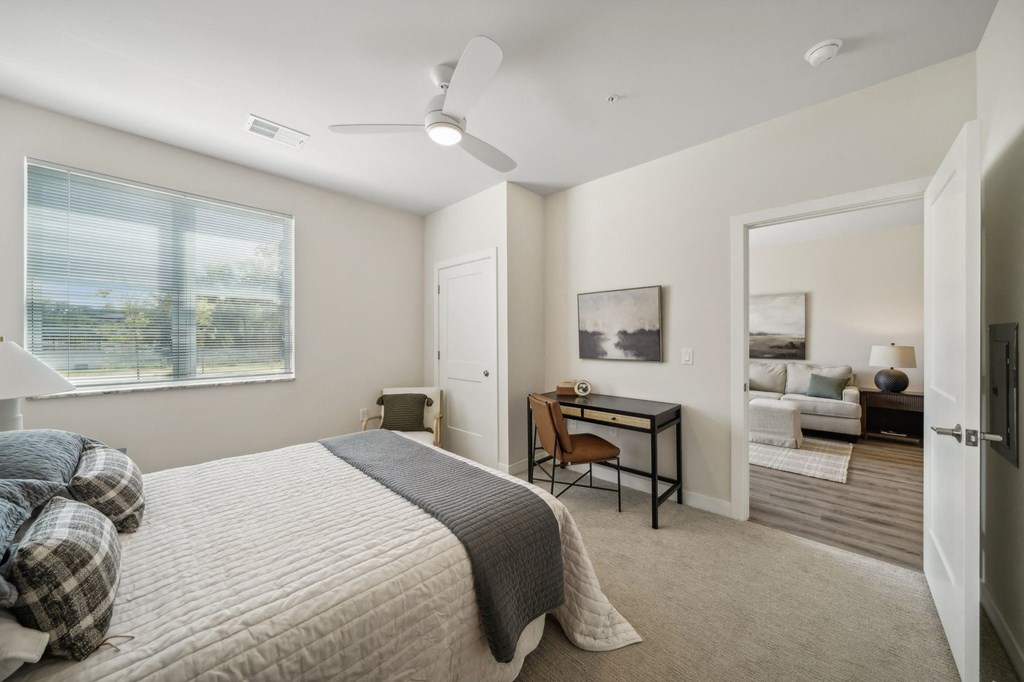 a bedroom with a bed and a desk with a window