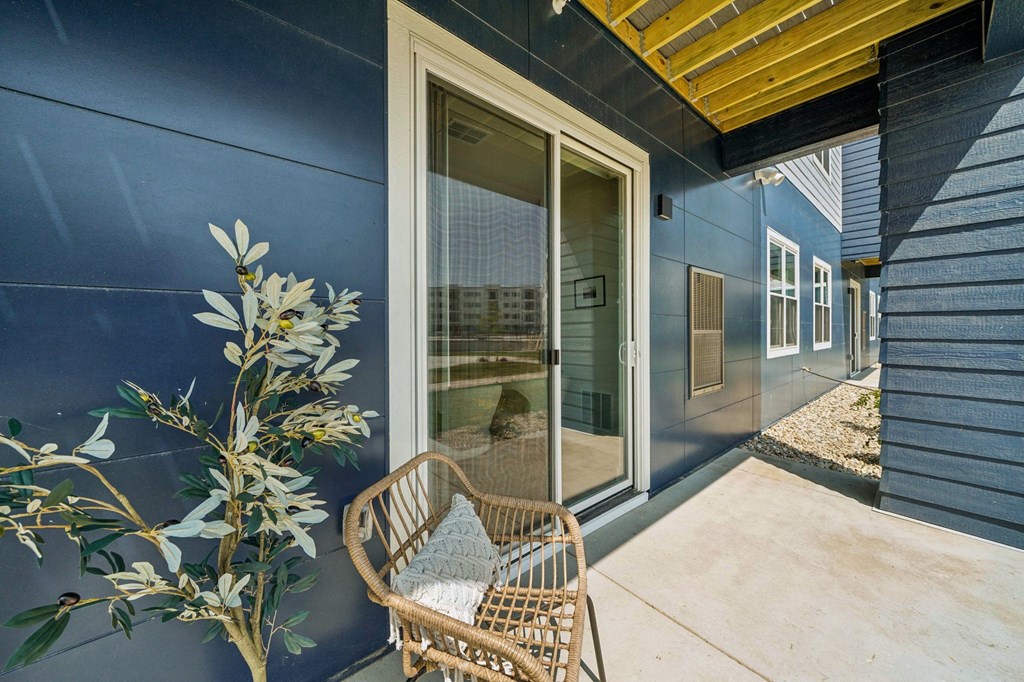 a patio with a chair and a blue wall with a glass door