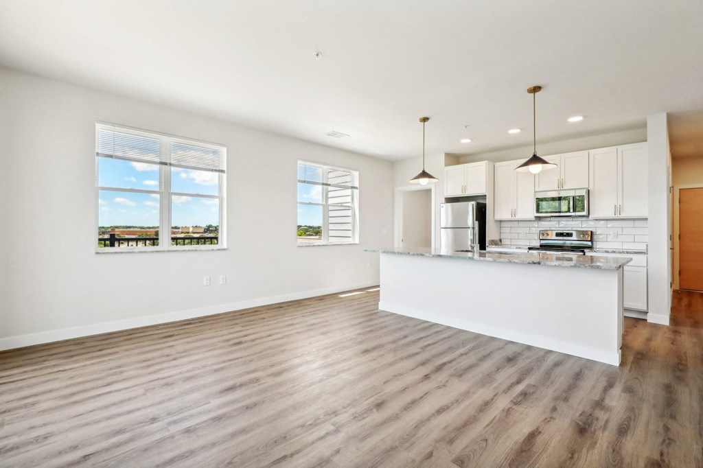 an open kitchen and living room with white walls and wood floors