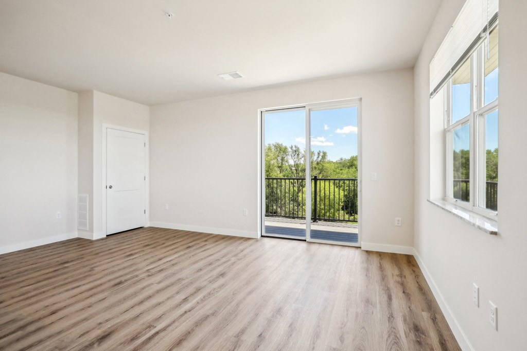 an empty living room with wood flooring and sliding glass doors
