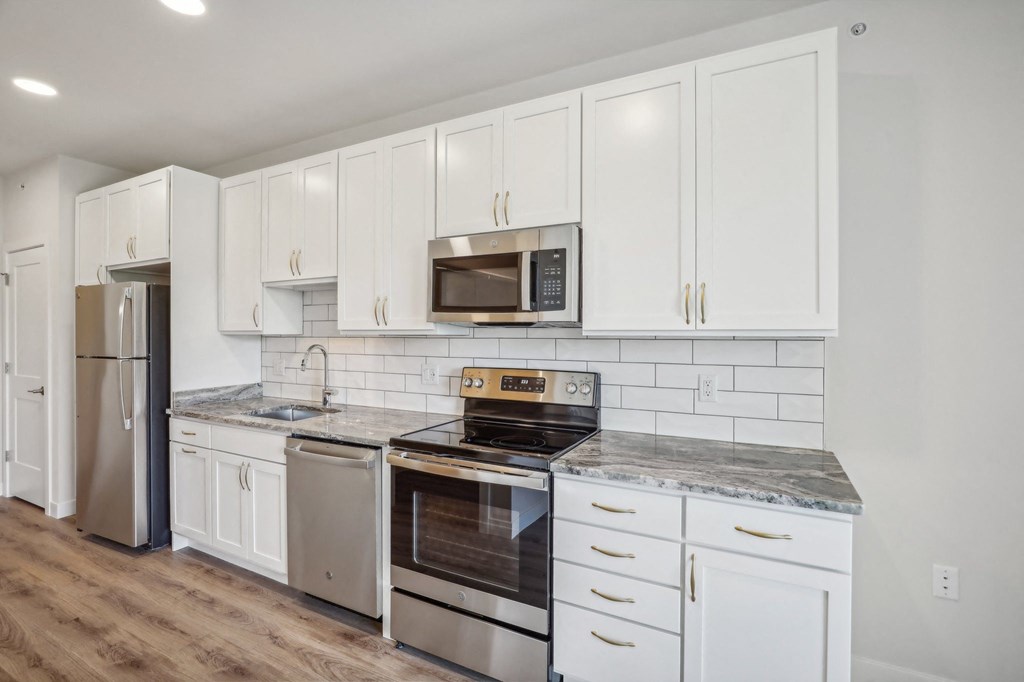 a white kitchen with stainless steel appliances and white cabinets