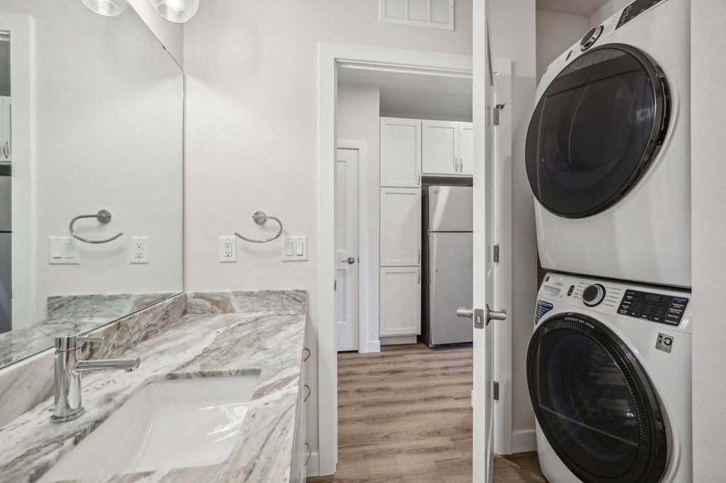 a washer and dryer in a laundry room with a sink and a mirror