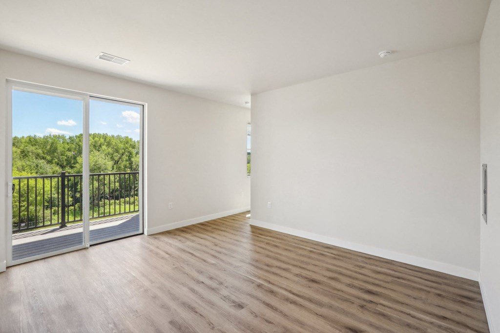 an empty living room with a balcony and wood flooring