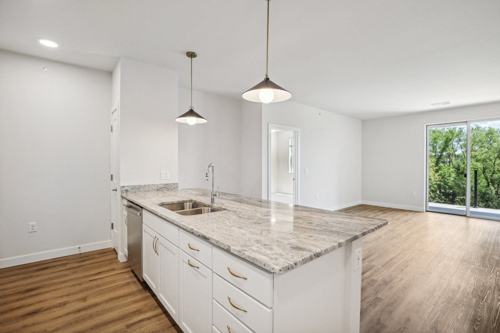 a kitchen with white cabinets and a marble counter top