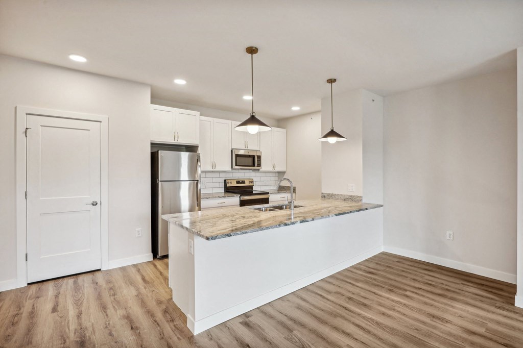 a kitchen with white cabinets and a marble counter top