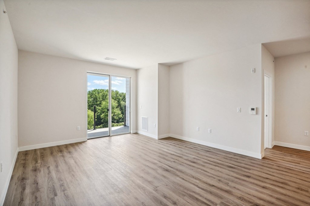 an empty living room with wood floors and a sliding glass door