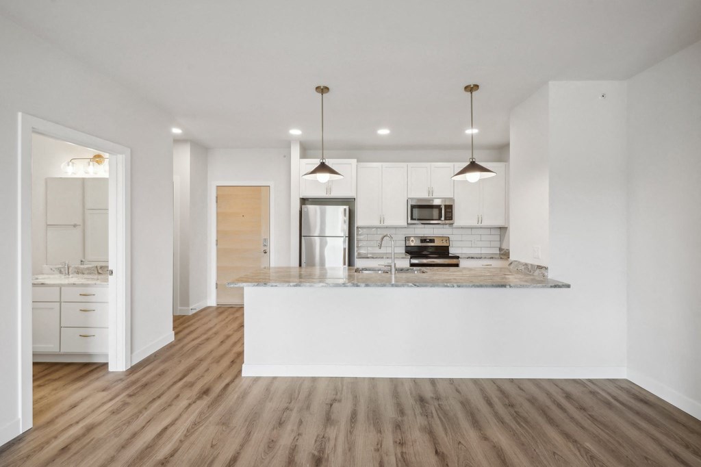 a kitchen with white cabinets and a marble counter top