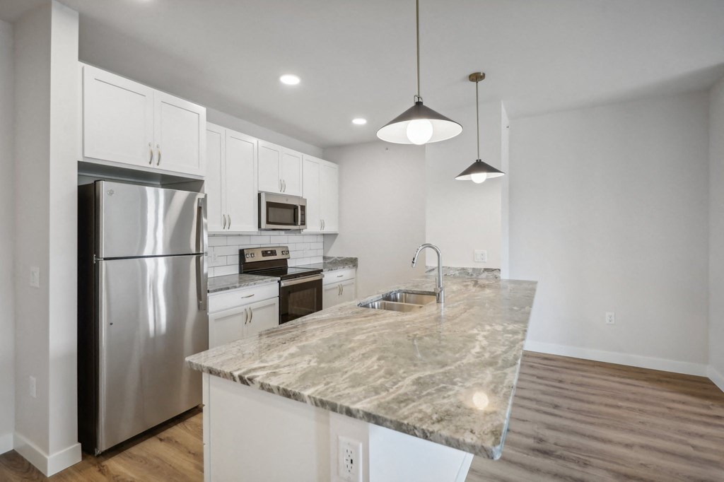 a kitchen with a marble counter top and a stainless steel refrigerator