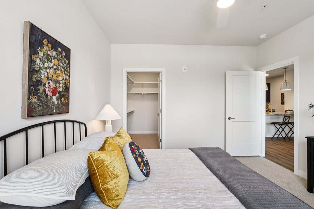 A bedroom with a bed, a lamp, and a painting on the wall.