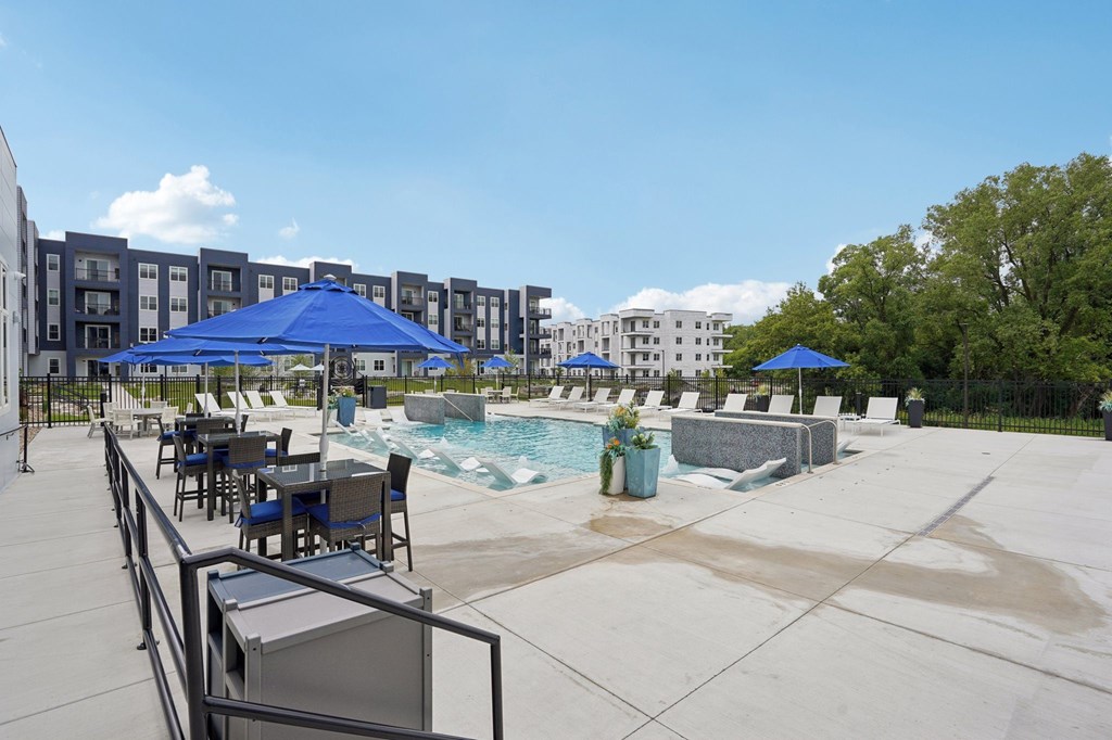 A pool area with a table and chairs and umbrellas.