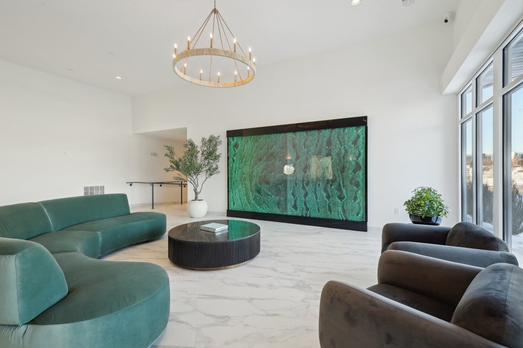 A living room with a green couch and a large painting on the wall.
