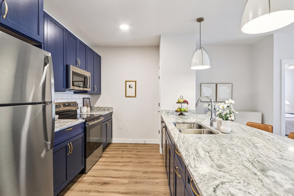 A kitchen with a marble countertop and blue cabinets.