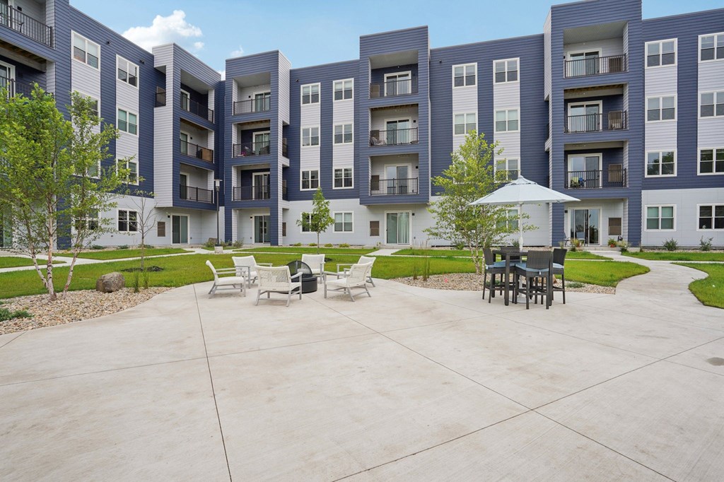 A large building with a patio and chairs in front.