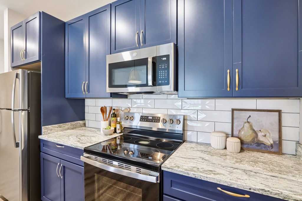 A kitchen with blue cabinets and a stove top oven.