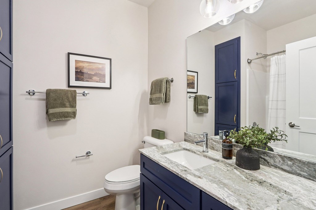 A bathroom with a toilet, sink, and a mirror.