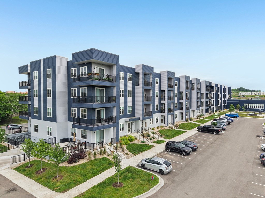 A row of modern apartment buildings with cars parked in the driveway.