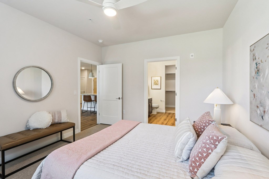 A bedroom with a large bed and a mirror on the wall.