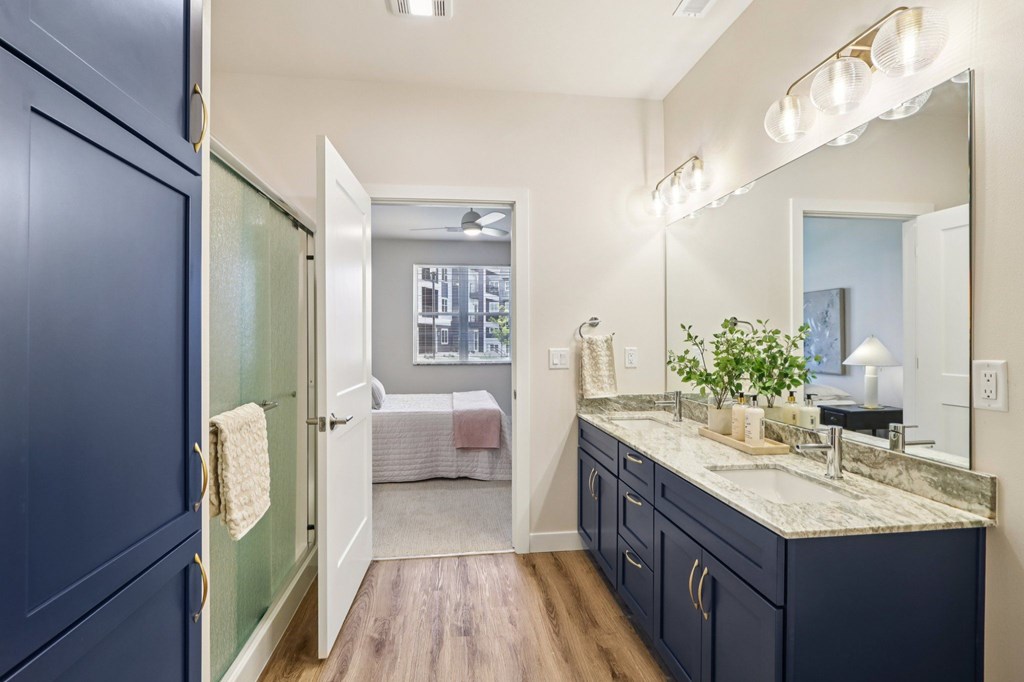 A bathroom with a dark blue cabinet and a mirror above the sink.
