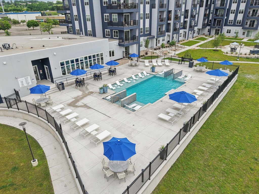 A pool surrounded by a black fence and blue umbrellas.