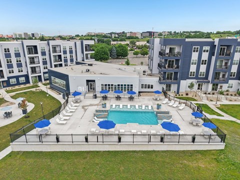 A large swimming pool surrounded by lounge chairs and umbrellas in the middle of a grassy area.