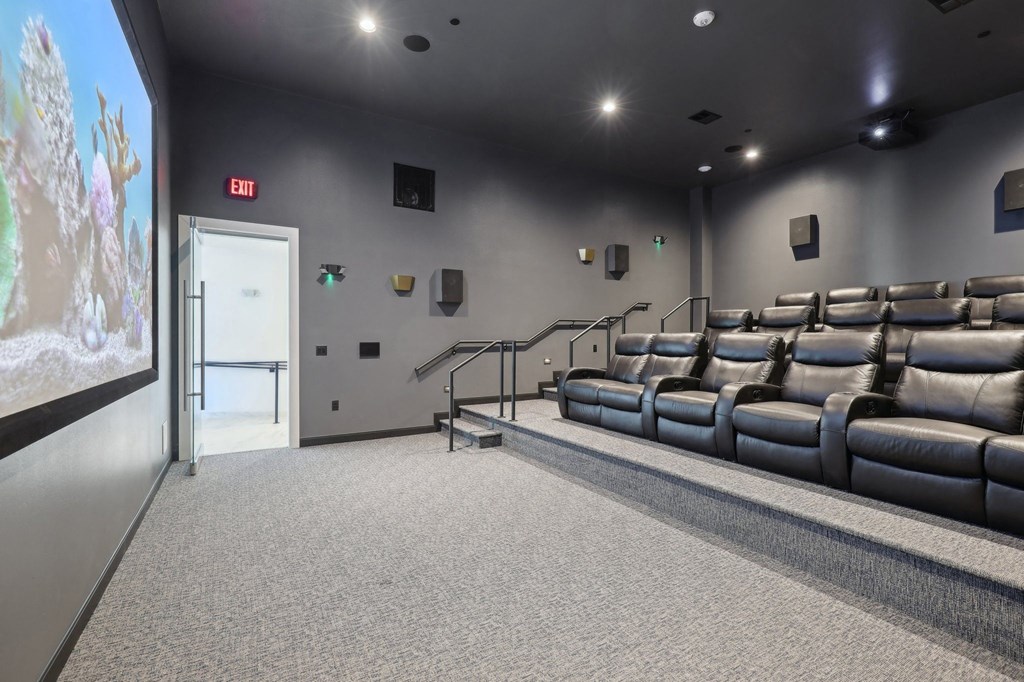 A cinema room with a row of seats and a screen on the left.