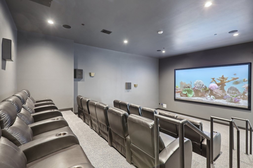 A row of seats in a theater with a large screen at the front.