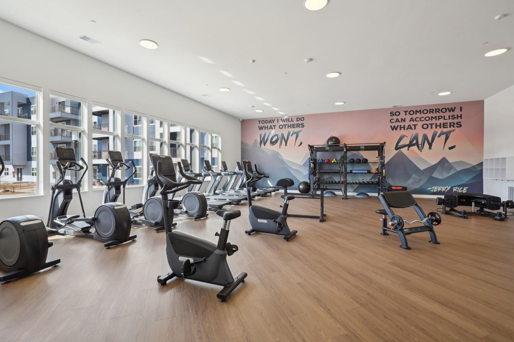 A gym with a variety of equipment and a motivational poster on the wall.